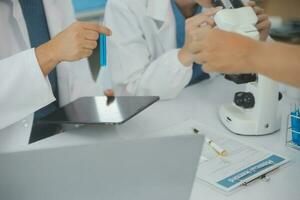 Health care researchers working in life science laboratory. Young female research scientist and senior male supervisor preparing and analyzing microscope slides in research lab. photo