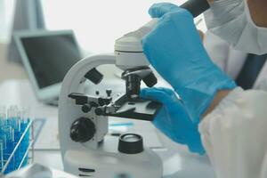 investigadores de atención médica que trabajan en el laboratorio de ciencias de la vida. joven científica investigadora y supervisora masculina senior preparando y analizando portaobjetos de microscopio en el laboratorio de investigación. foto