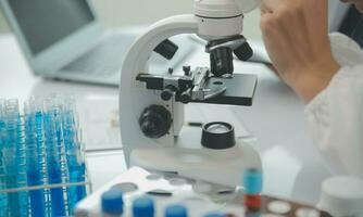 investigadores de atención médica que trabajan en el laboratorio de ciencias de la vida. joven científica investigadora y supervisora masculina senior preparando y analizando portaobjetos de microscopio en el laboratorio de investigación. foto