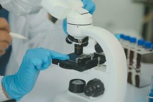 investigadores de atención médica que trabajan en el laboratorio de ciencias de la vida. joven científica investigadora y supervisora masculina senior preparando y analizando portaobjetos de microscopio en el laboratorio de investigación. foto