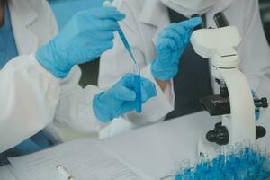 Health care researchers working in life science laboratory. Young female research scientist and senior male supervisor preparing and analyzing microscope slides in research lab. photo