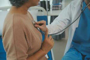 Doctor use stethoscope, checking up heart beat, lunch of auscultation in doctor office at hospital. Patient worker has to get medical checkup every year for her health or medical checkup cardiologist photo