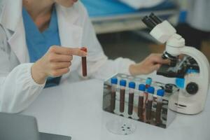 Health care researchers working in life science laboratory. Young female research scientist and senior male supervisor preparing and analyzing microscope slides in research lab. photo