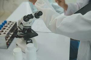 Health care researchers working in life science laboratory. Young female research scientist and senior male supervisor preparing and analyzing microscope slides in research lab. photo