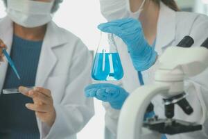 investigadores de atención médica que trabajan en el laboratorio de ciencias de la vida. joven científica investigadora y supervisora masculina senior preparando y analizando portaobjetos de microscopio en el laboratorio de investigación. foto