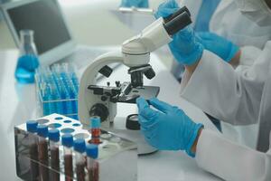 investigadores de atención médica que trabajan en el laboratorio de ciencias de la vida. joven científica investigadora y supervisora masculina senior preparando y analizando portaobjetos de microscopio en el laboratorio de investigación. foto