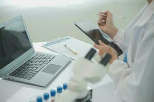 Health care researchers working in life science laboratory. Young female research scientist and senior male supervisor preparing and analyzing microscope slides in research lab. photo