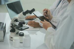 Health care researchers working in life science laboratory. Young female research scientist and senior male supervisor preparing and analyzing microscope slides in research lab. photo