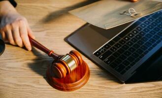 Justice and law concept.Male judge in a courtroom with the gavel, working with, computer and docking keyboard, eyeglasses, on table in morning light photo