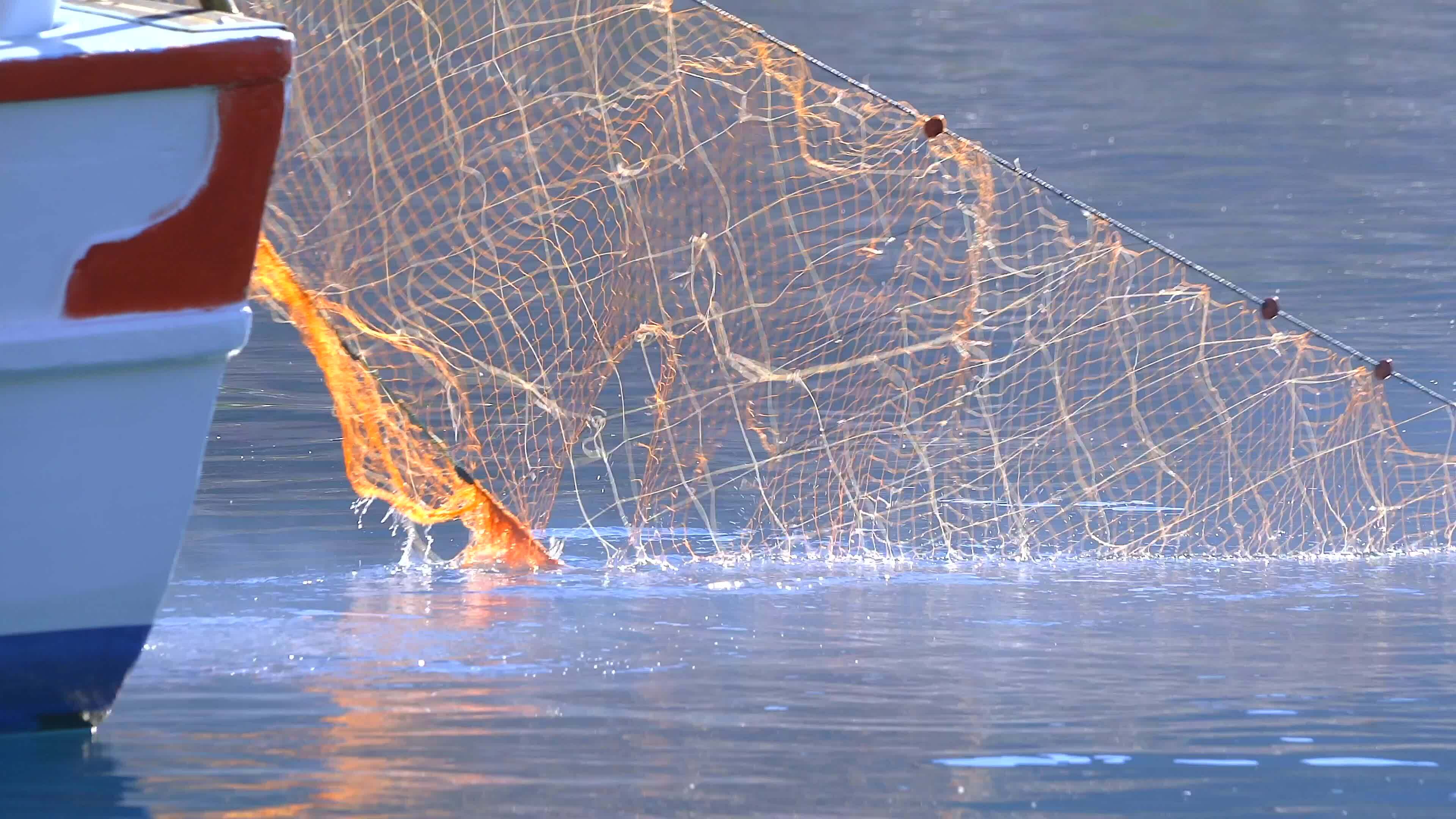 A Net Off is Thrown Into the Sea From a Small Fishing Boat