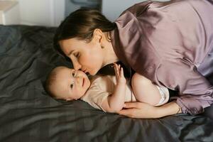 madre Besos su bebé en el cama foto