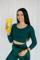 atlético joven mujer participación un botella de agua después un rutina de ejercicio a hogar foto