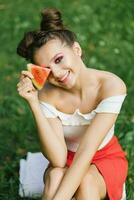 una niña sonriente sostiene una sandía dulce en sus manos y sonríe mientras se sienta en el césped foto