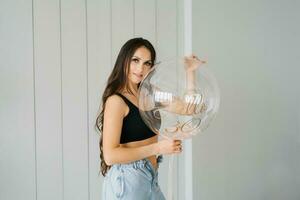 elegante hermosa joven caucásico mujer con largo pelo en un negro parte superior y pantalones sostiene un cumpleaños globo en honor de su trigésimo cumpleaños foto