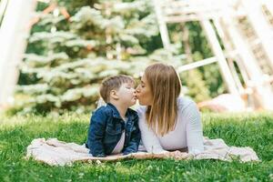 familia, mamá y su hijo mentira en el césped en el parque en verano y Beso foto