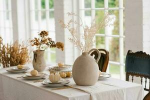 acción de gracias mesa ajuste con calabazas y seco flores, otoño decoraciones en un moderno comida habitación en Clásico estilo foto