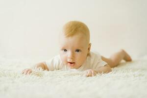 A five-month-old baby is lying on his stomach on the bed. The concept of caring for a baby photo
