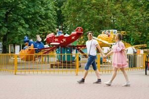 joven contento Pareja en amor camina y tiene divertido en un diversión parque foto