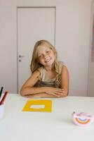 Caucasian girl is sitting at a desk with a notebook and stationery on it and smiling photo