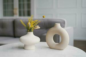 Two decorative ceramic modern round vases with a hole inside on the table in the living room photo