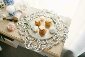 Delicious sweets on a beautiful silver glass tray on the table. Candy bar at a wedding or party photo