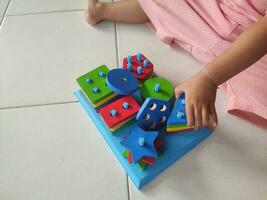 Baby playing with educational toy. Geometric montessori toy played by baby. photo