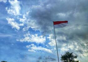 Indonesian national flags against blue sky. Red white flag flies on a pole. photo