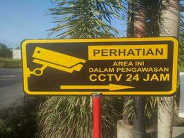 Warning sign board installed in front of residential gate.Which means the area is being watched by CCTV 24 hours. photo