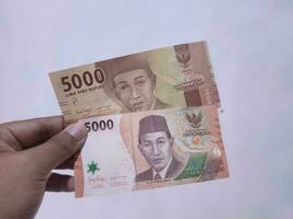 The old and new five thousand rupiah notes are hand-held. Rupiah is the currency of Indonesia. photo