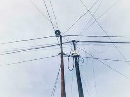 Electric poles with tangled wires with clouds background photo