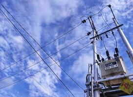 Power transformer of electricity with many transverse cables with sky background photo