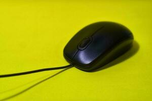 Black computer mouse isolated on yellow background photo