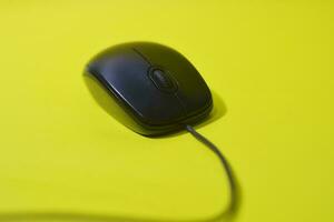 Black computer mouse isolated on yellow background photo