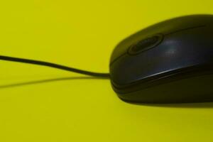 Black computer mouse isolated on yellow background photo