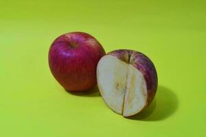 Piece of red apple isolated on yellow background photo