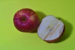 Piece of red apple isolated on yellow background. Flat lay photo