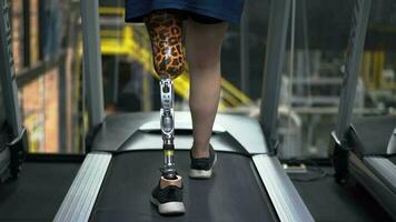 femme avec prothétique jambe en utilisant en marchant sur une tapis roulant tandis que travail en dehors dans le salle de sport. video