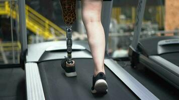 Woman with prosthetic leg using walking on a treadmill while working out in the gym. video