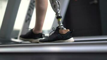 Woman with prosthetic leg using walking on a treadmill while working out in the gym. video