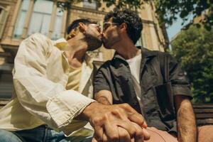 men sitting on a bench in the city kissing ang huging each other photo