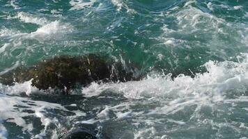 meerblaue welle stürzt gegen stein. aufgewühltes Meer video