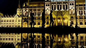 Nigh shot of Budapest parliament with water reflection and silhouettes walking by video