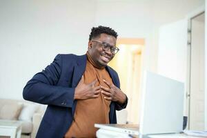 Heart attack. Young businessman in sitting and and holding his chest because feeling pain on his heart. business and freelancing concept. indoor shot photo