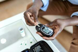 joven africano hombre utilizando digital glucómetro a hogar. diabetes controlar foto