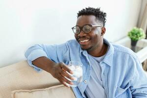 Young African man in casualwear drinking water from glass photo