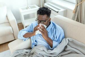 Portrait of a sick man with the flu, allergy, germs,cold coughing. Sick Man with headache sitting under the blanket with high fever and a flu, resting and drinking hot beverage photo