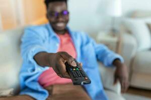 Excited African American Man Pointing Television Controller To Camera Switching Channels Watching TV . Television Programming Advertisement. Selective Focus photo