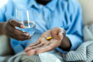 Black man hold pills and jar in his hands. Concept of healthcare and medicine, patient take daily dose of prescribed medicament, feel sick, antibiotics, painkillers or antidepressants. Close up photo