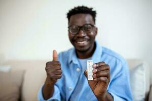 afroamericano hombre participación un negativo prueba dispositivo. contento joven hombre demostración su negativo coronavirus - covid-19 rápido prueba. coronavirus foto