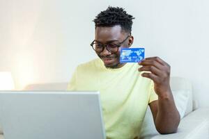 pago en línea, joven con tarjeta de crédito y computadora portátil para compras en línea. concepto de viernes negro o lunes cibernético. hombre pagando con tarjeta de crédito en una laptop en la oficina de casa foto